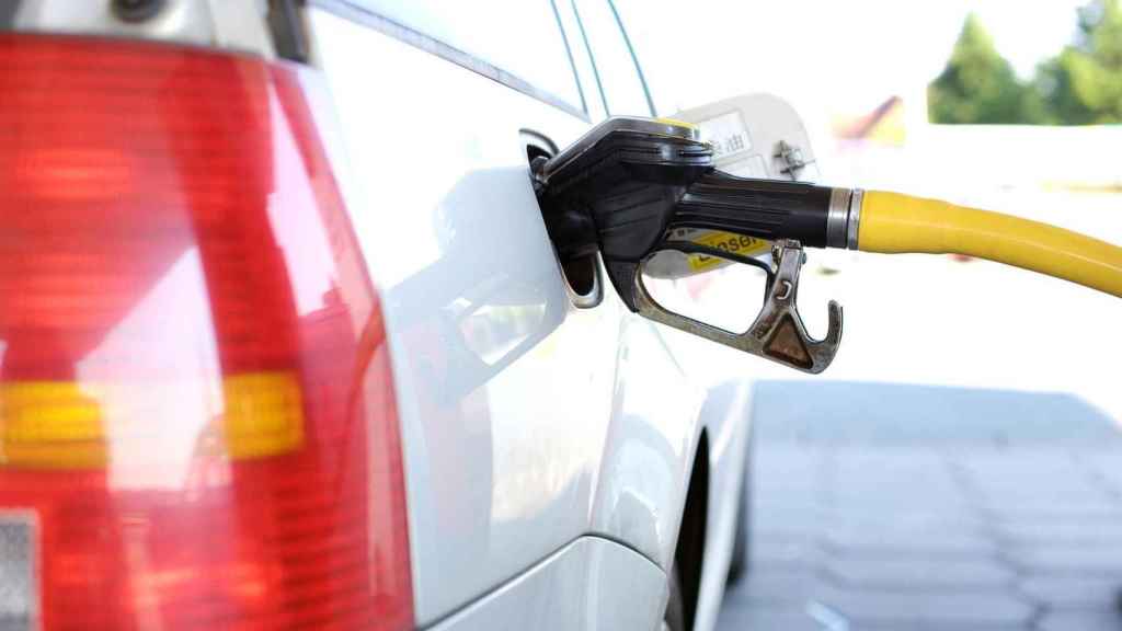 Un automóvil con la manguera de gasolina llenando su depósito