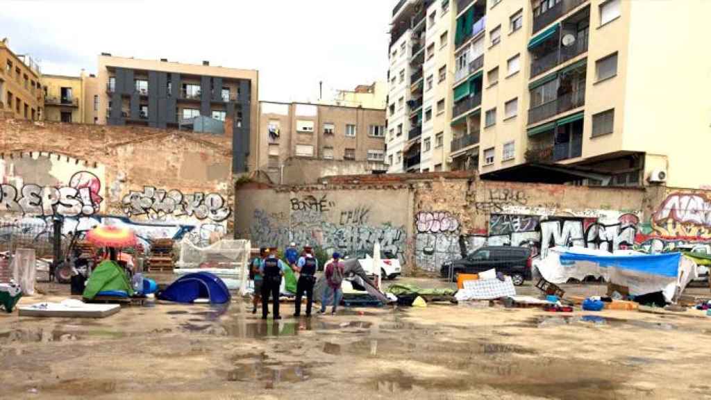 Dos agentes de los Mossos d'Esquadra, requiriendo a los acampados en un solar de Arco de Triunfo / MJC