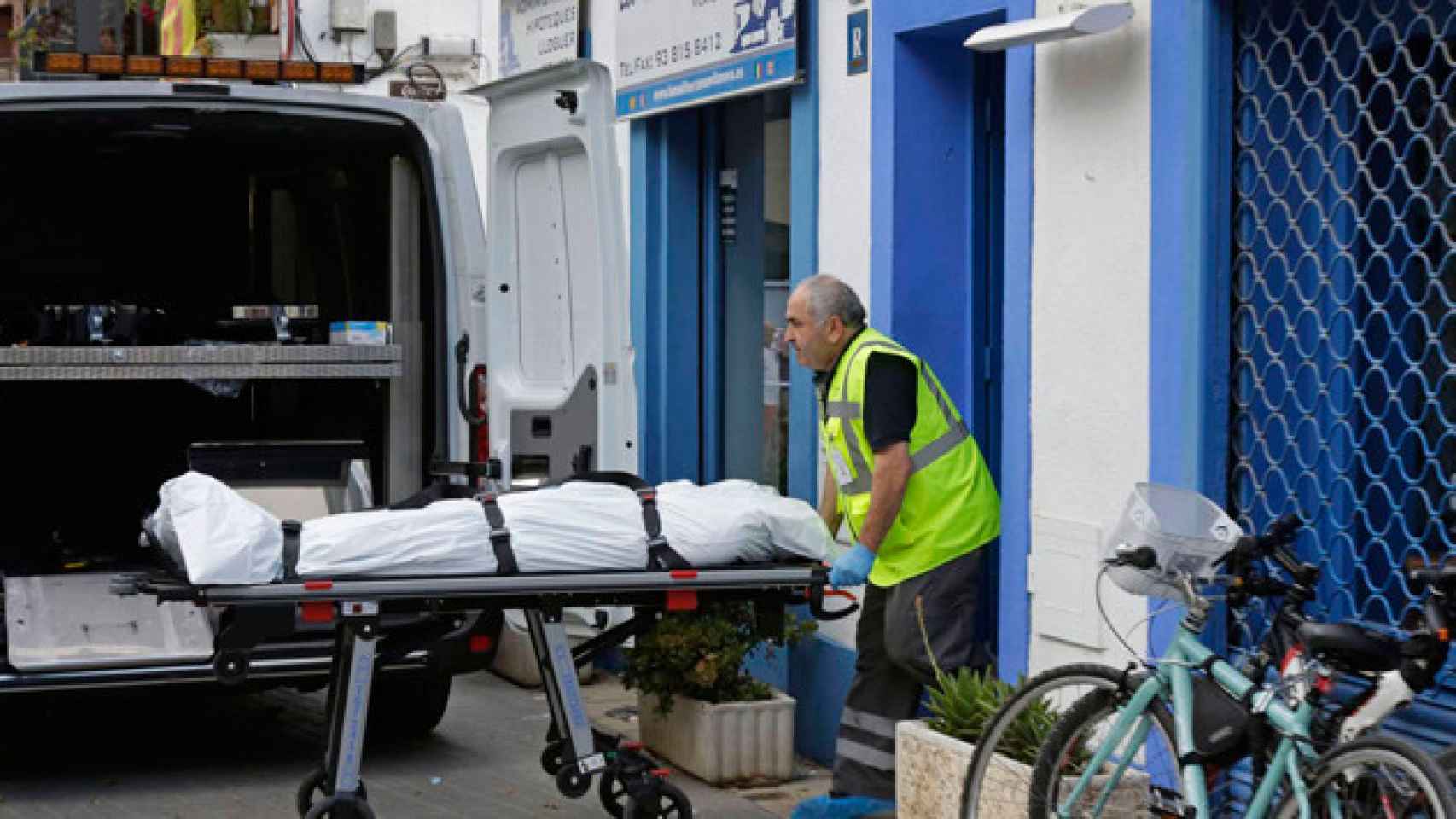 Un empleado de una funeraria saca el cadáver del compañero sentimental de la propietaria del bar / EFE