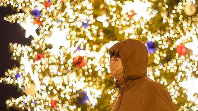 Imagen de un hombre con mascarilla contra el coronavirus ante un árbol navideño / EFE