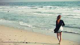 Una mujer camina por la playa / CD