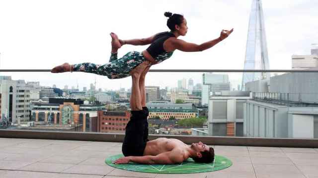 Una pareja realizando una postura de yoga / PEXELS