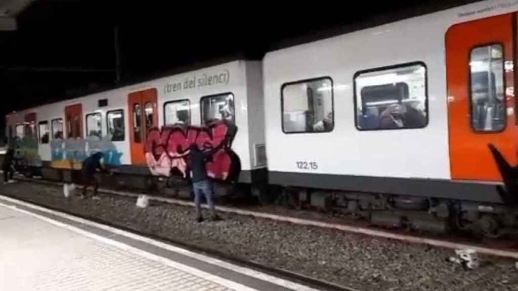 Un grupo de grafiteros, pintando un convoy de Ferrocarrils de la Generalitat / @AdnCataluna (TWITTER)