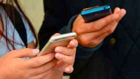 Dos adolescentes con sus móviles en la mano