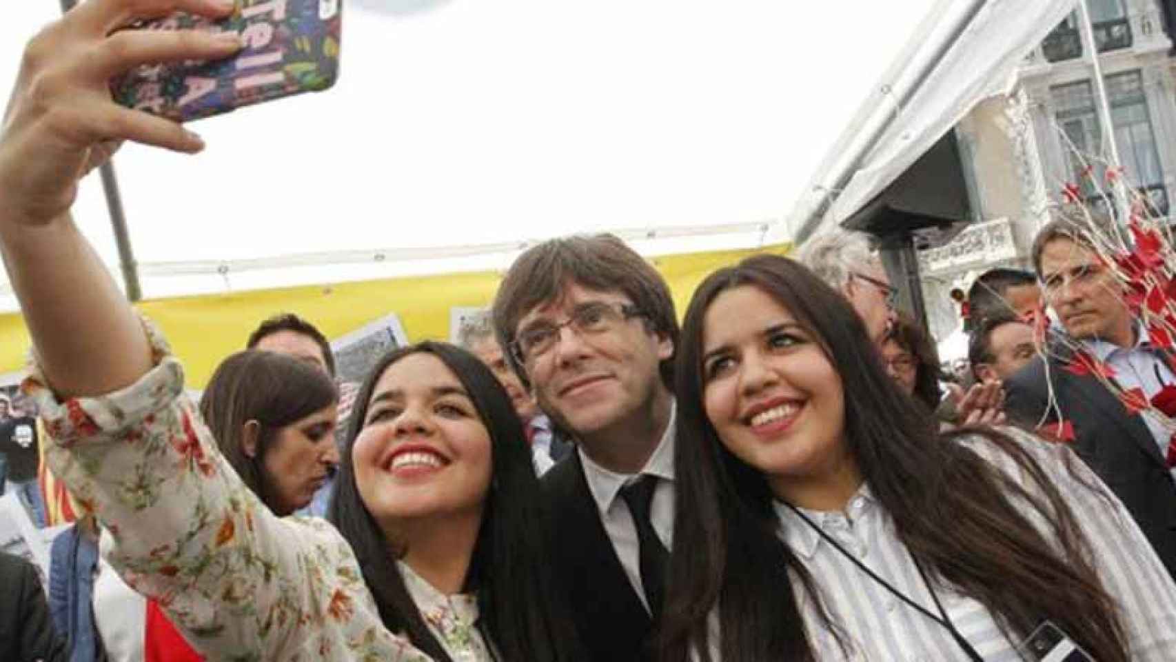 El presidente de la Generalitat Carles Puigdemont se hace un 'selfie' con dos gemelas / EFE