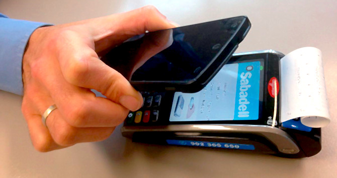 Un móvil se acerca a un datáfono para efectuar un pago