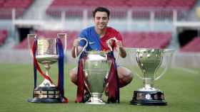 Xavi Hernàndez con los tres títulos que cosechó el FC Barcelona en la temporada 2008-09 / EFE