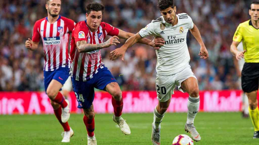 Marco Asensio aguanta el balón durante el partido que enfrentó a Real Madrid y Atlético / EFE