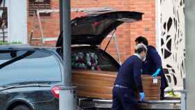 Dos funerarios colocan un féretro en un coche fúnebre en Madrid en plena pandemia / EFE