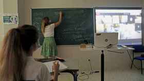 Una profesora escribe en la pizarra durante una clase / EP