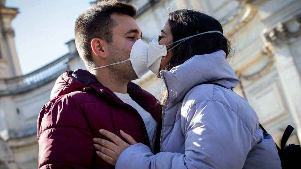 Una pareja se besa con las mascarillas puestas / EFE