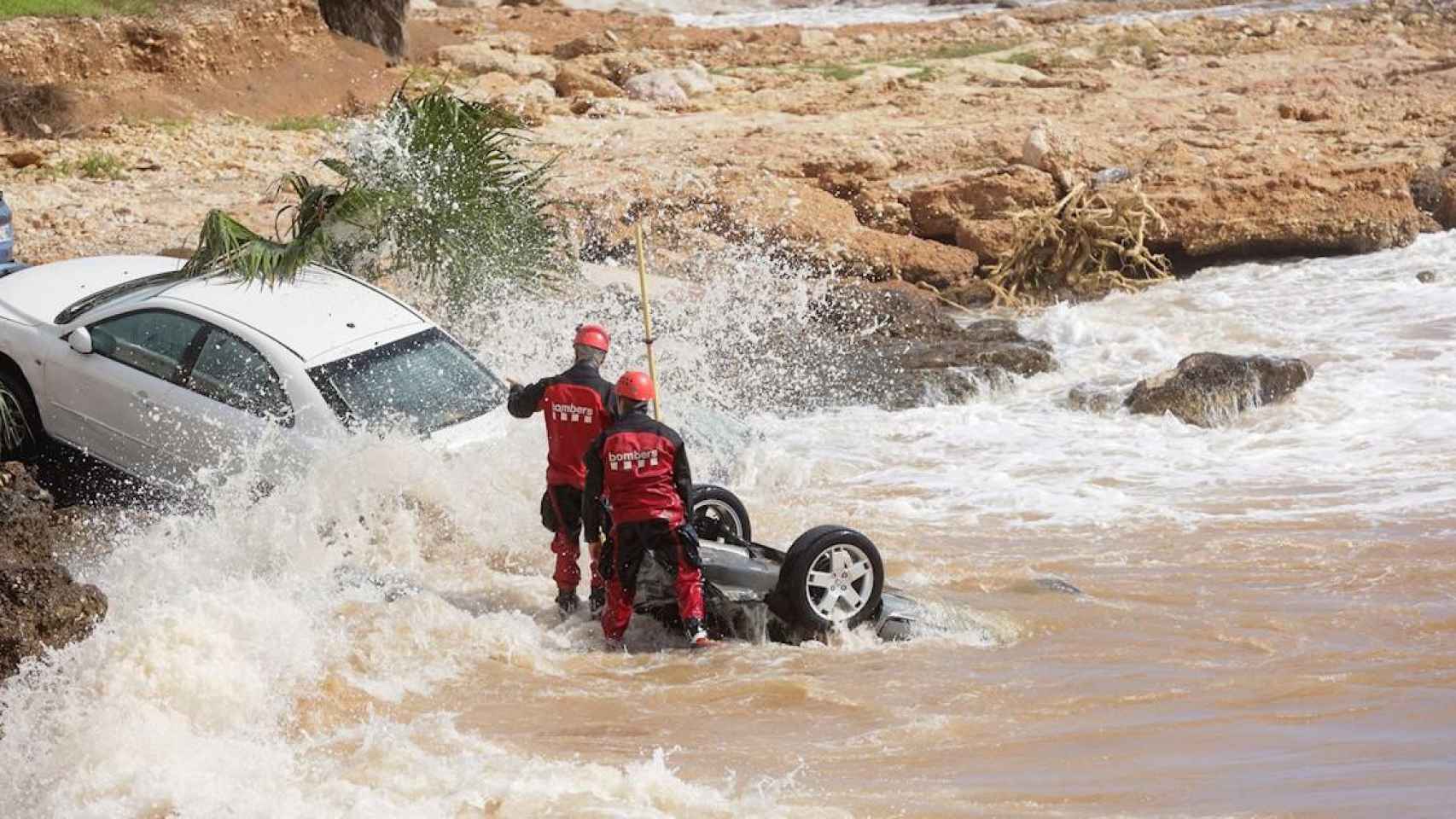 Dos bomberos en les Cases d'Alcanar, donde varios coches han sido arrastrados por las lluvias / QUIQUE GARCÍA - EFE