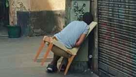 Una persona, durmiendo en una silla abandonada en el Raval / CG