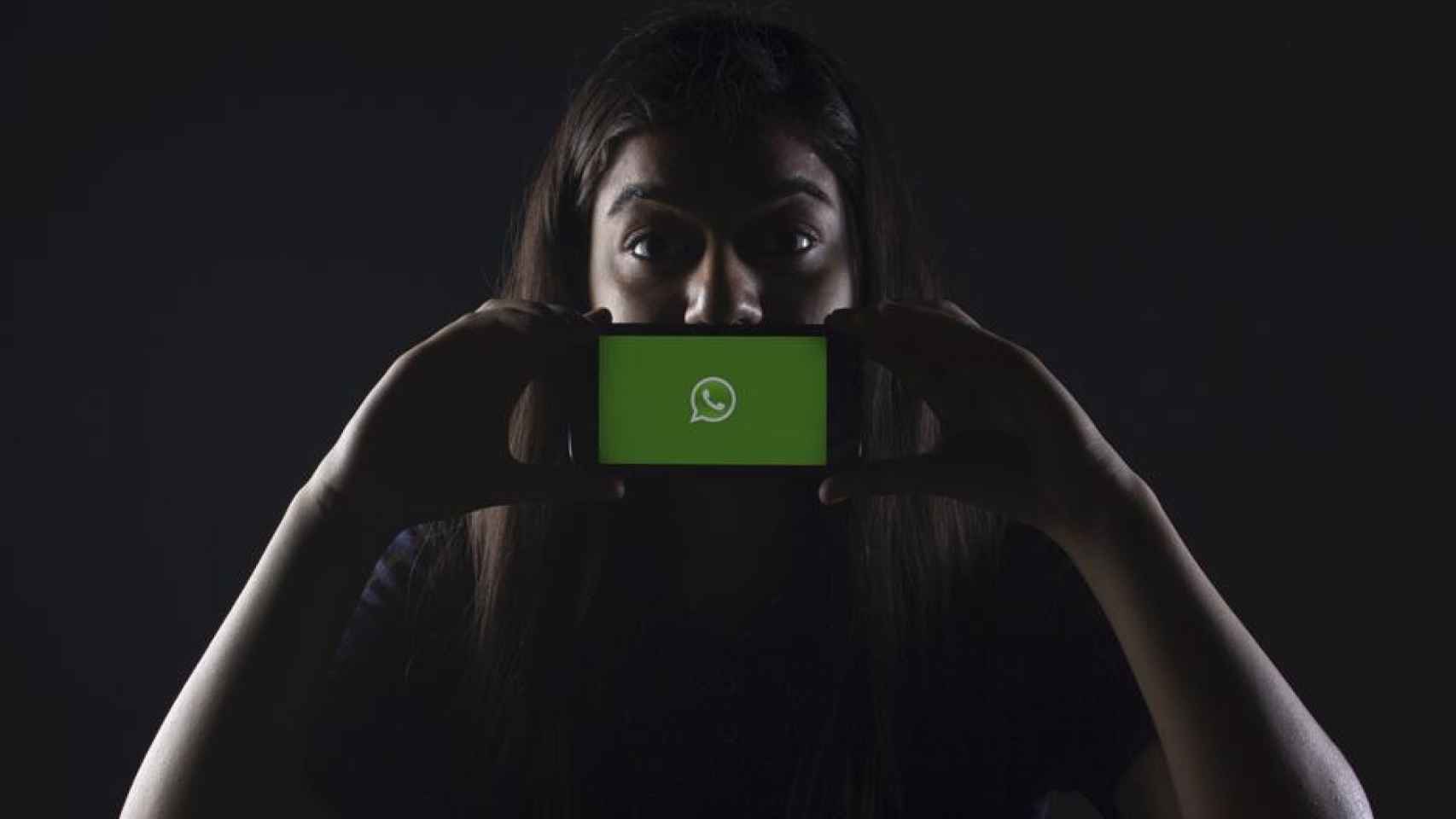 Mujer enseñando su móvil con WhatsApp / UNSPLASH