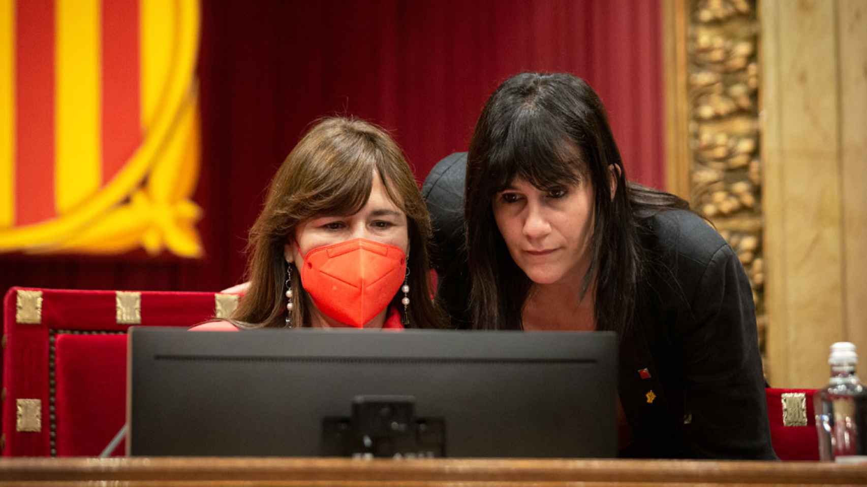 Laura Borràs (i), presidenta del Parlament, consultando su ordenador / EP