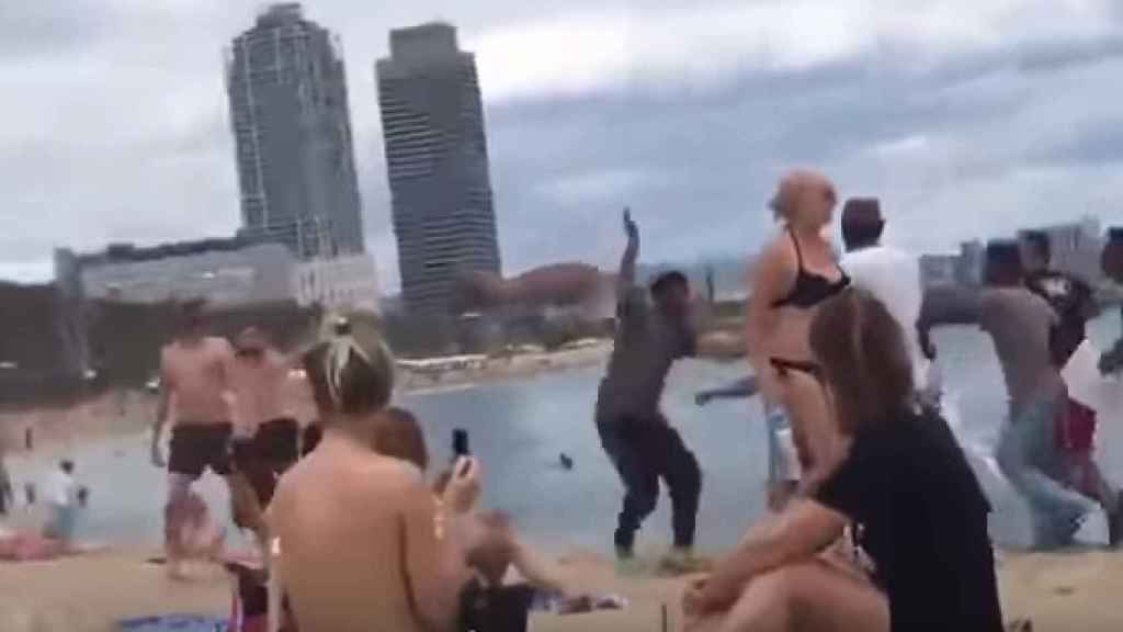 Bañistas observan la pelea entre manteros en la Barceloneta