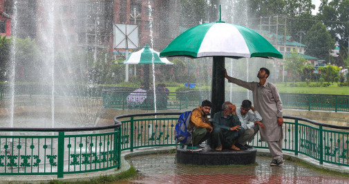 Varias personas se refugian bajo las marquesinas en un parque durante la lluvia en Srinagar, la capital de verano de la Cachemira india este jueves - EFE/FAROOQ KHAN