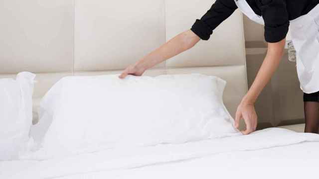 Una camarera de piso hace la cama de la habitación de un hotel / EFE