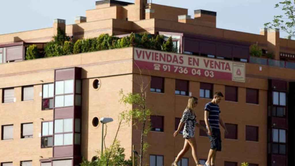 Dos jóvenes frente a un cartel de venta de viviendas / EFE