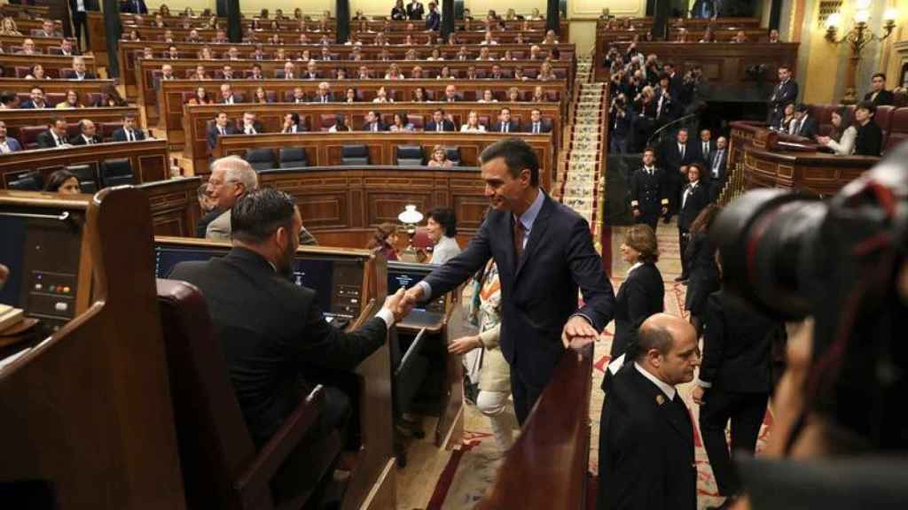 Pedro Sánchez traga saliva mientras saluda a Santiago Abascal, quien como el resto de los diputados de Vox se había colocado en la bancada socialista / EFE