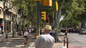 Un ciudadano arranca una a una las cintas amarillas que a modo de lazos alguien ha pegado en un semáforo / CG