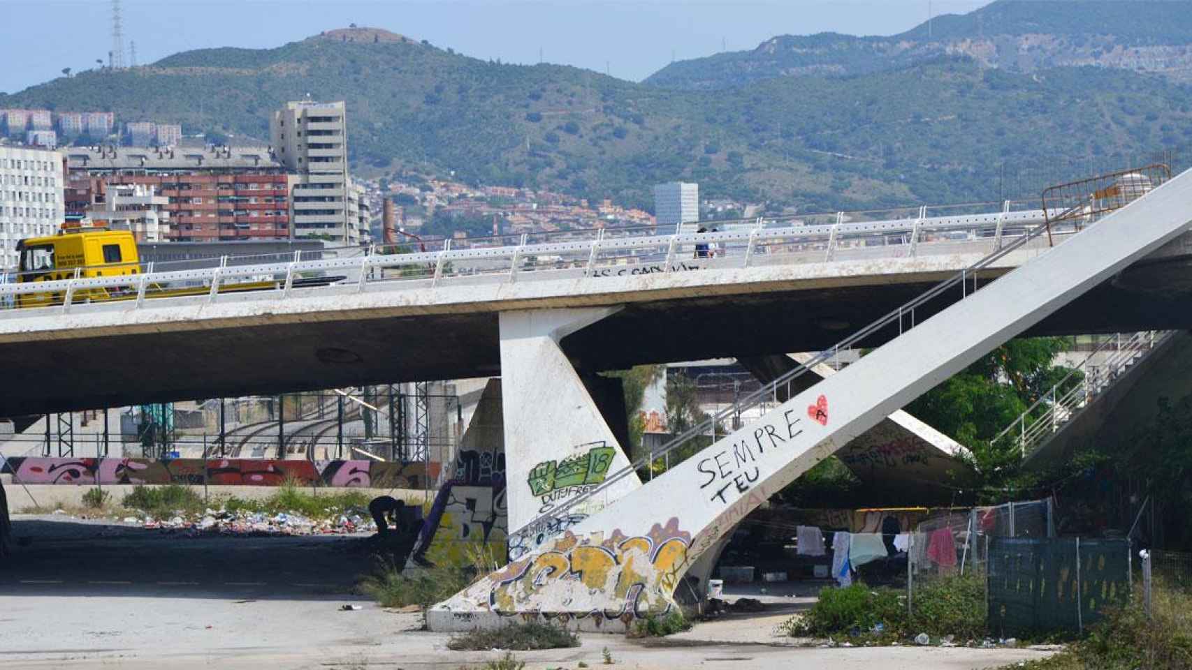 Un joven en el asentamiento bajo el puente de Bac de Roda en Barcelona, junto a ropa tendida / ELENA BURÉS