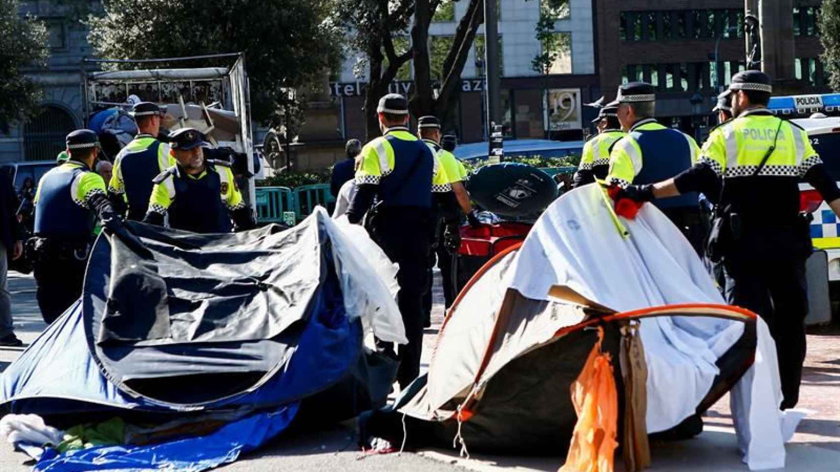 Agentes de la Guardia Urbana se llevan las tiendas durante el desalojo de Plaza Cataluña / EFE