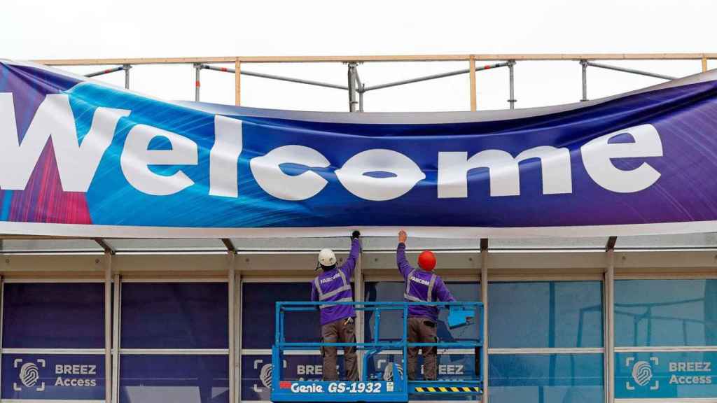 Operarios desmontando una de las pancartas de bienvenida del Mobile World Congress de Barcelona / EFE