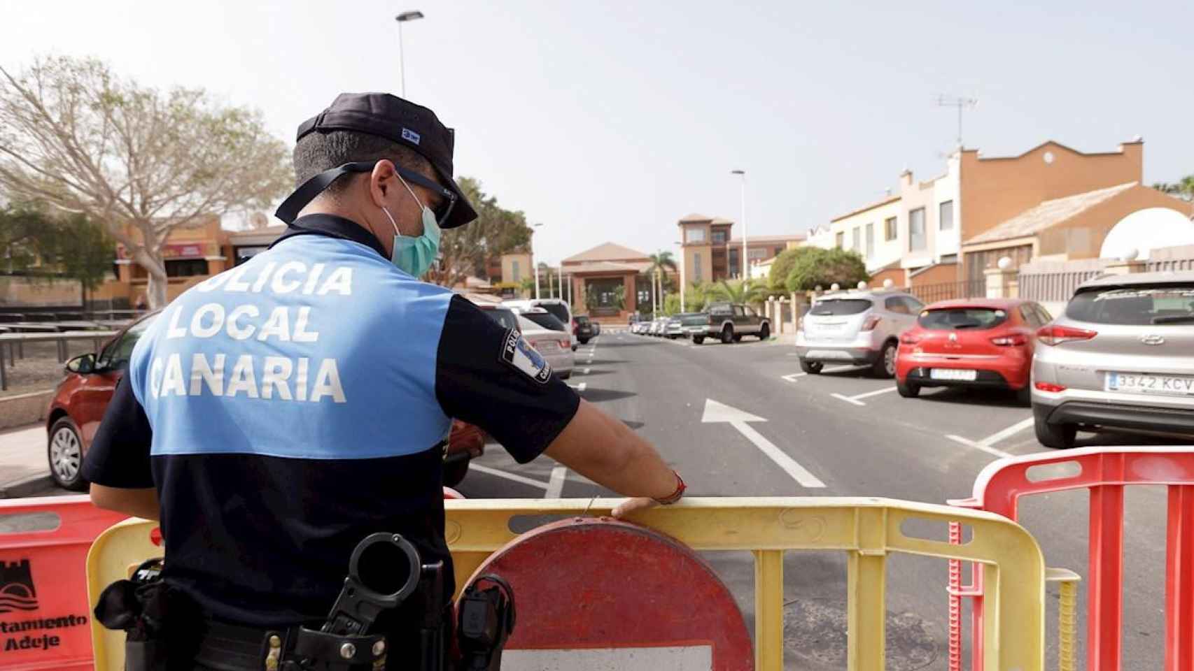 Un agente de policía coloca una valla para prohibir el paso al hotel situado en el municipio tinerfeño de Adeje, en el que se hospedaba la pareja que ha dado positivo por coronavirus / EFE