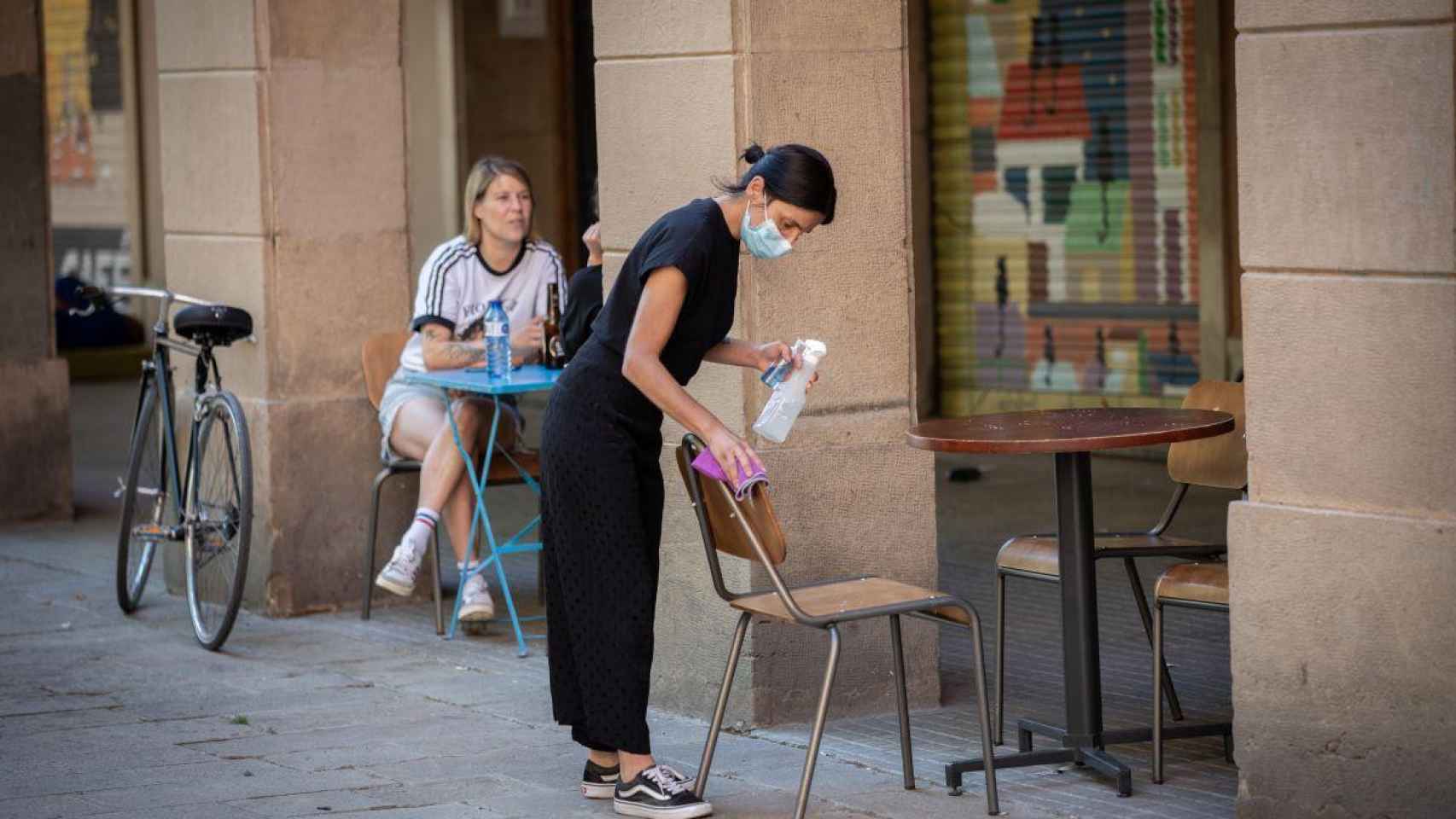 Una camarera limpia la terraza de un bar: muchos trabajadores aún esperan las ayudas del Govern  / EP