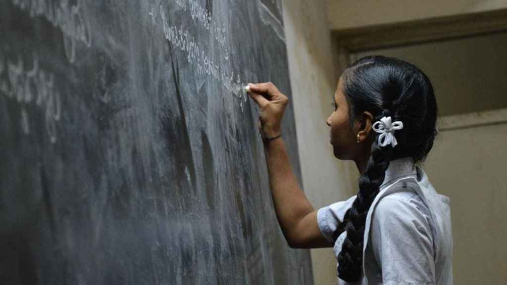 Niña escribiendo en la pizarra de una escuela / UNSPLASH