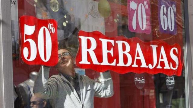 Un trabajador coloca los carteles de rebajas en un comercio / EFE