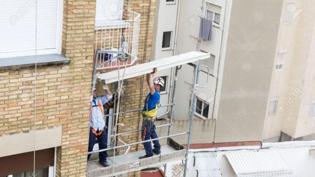 Trabajadores de la construcción reparando una fachada