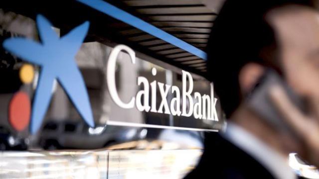 Un cliente ante una oficina de Caixabank, una de las empresas de la banca que alerta de los riesgos en Cataluña / CG