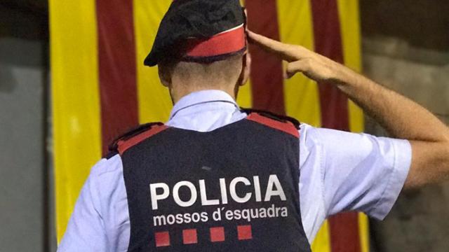Imagen de un agente de los Mossos d'Esquadra saludando a una estelada en Vic (Barcelona) / EFE