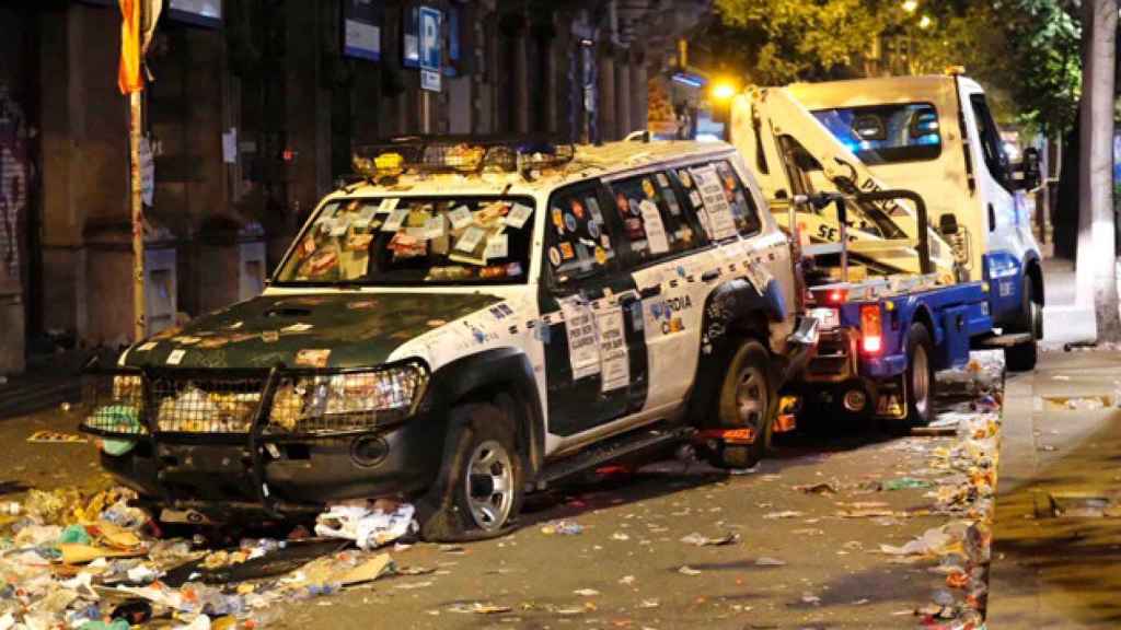 Una grúa retira un coche de la Guardia Civil con las ruedas pinchadas tras el vandalismo de los manifestantes / CG