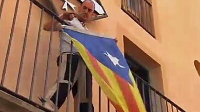 El alcalde de Miravet (Tarragona), Antoni Joan Borrell, retirando la 'estelada' de la fachada del Ayuntamiento