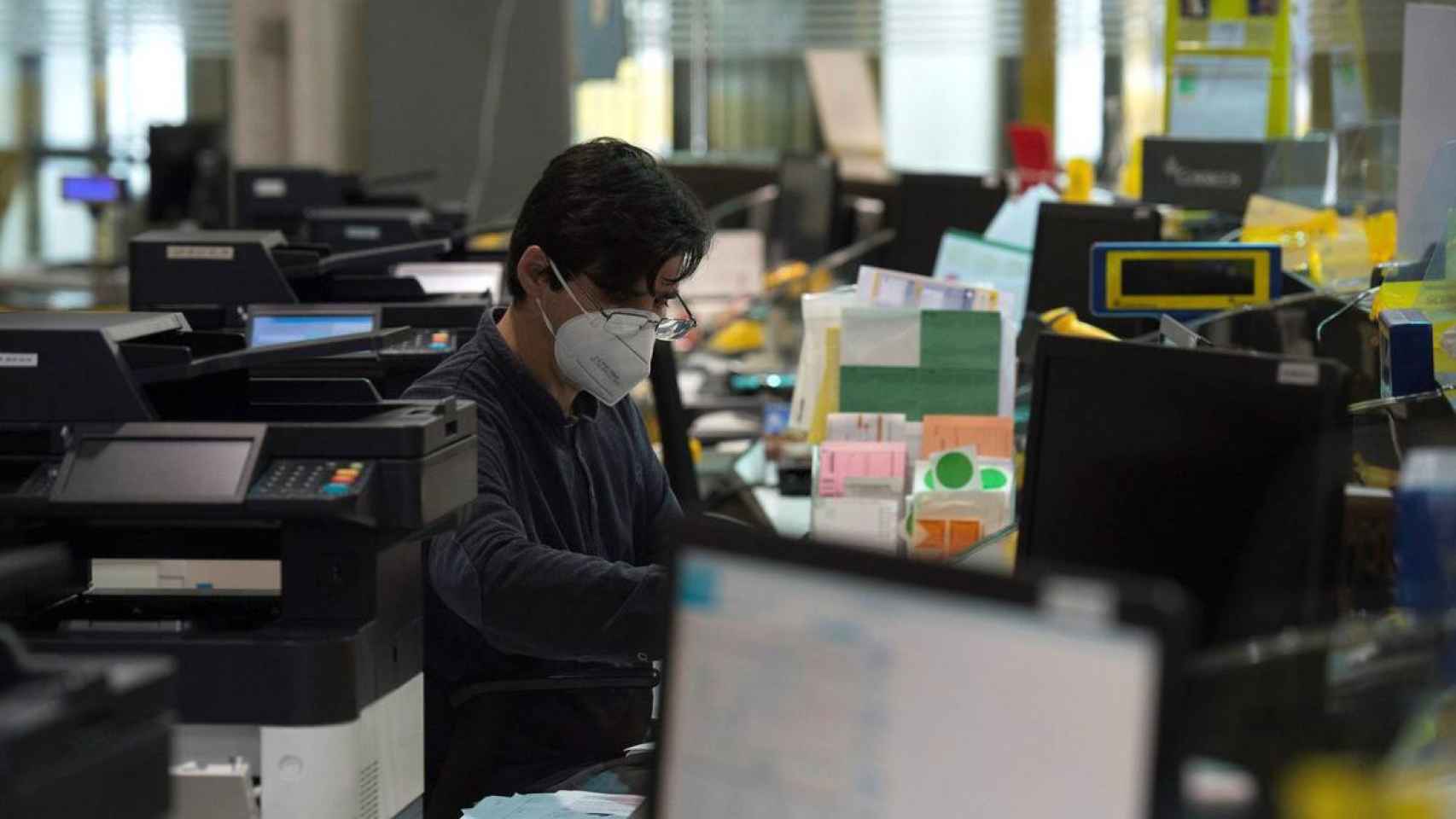 Un trabajador en una oficina con mascarilla / EFE