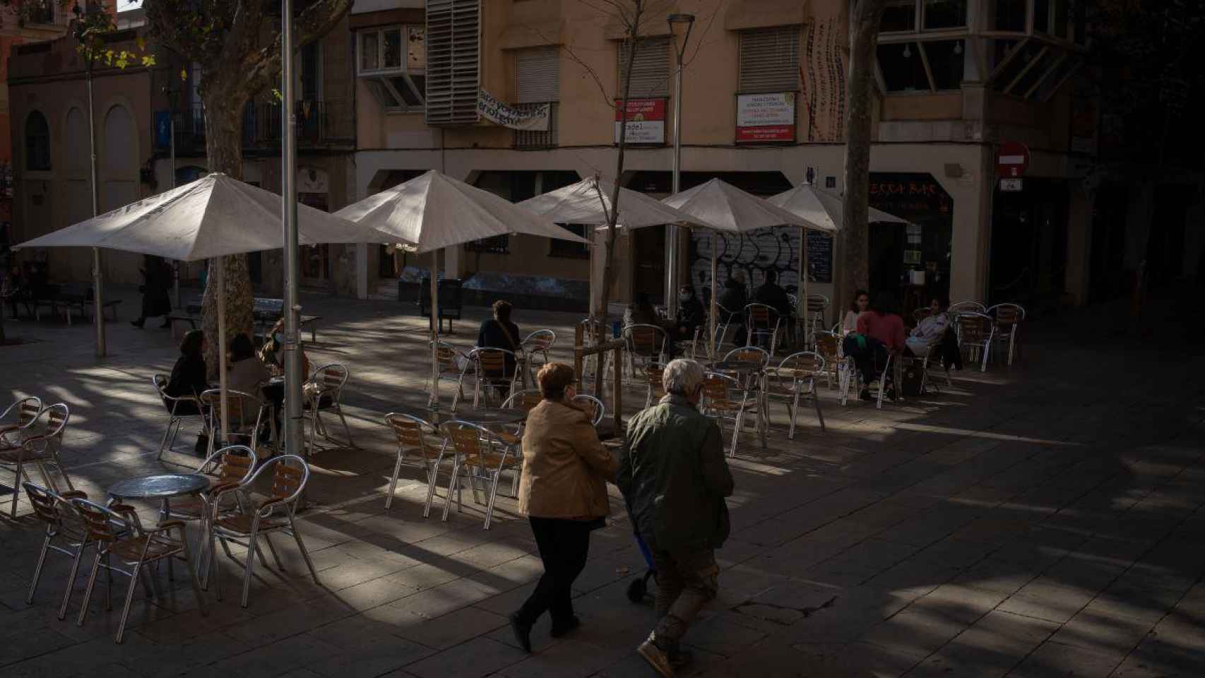 Dos personas pasean delante de una terraza semivacía por las restricciones a la resturación / EP