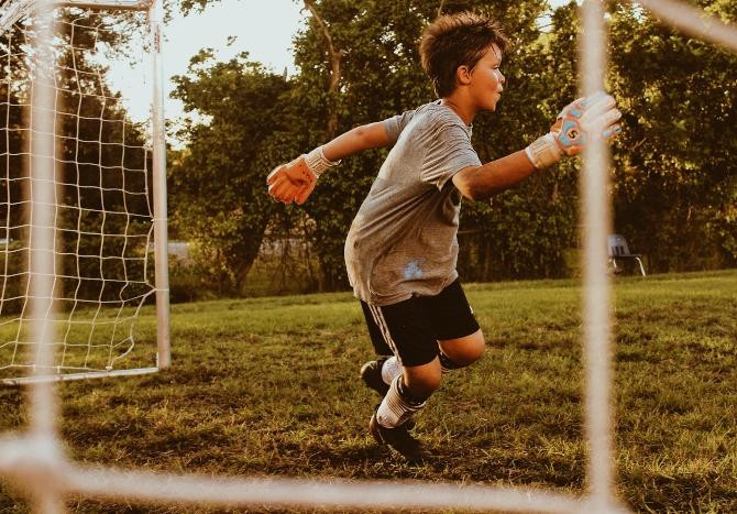 Niño practicando fútbol en un campamento de verano / Baylee Gramling en UNSPLASH