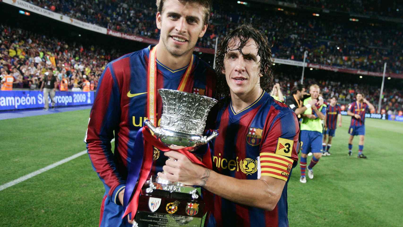 Gerard Piqué y Carles Puyol, sujetando el título de la Supercopa de España / FCB