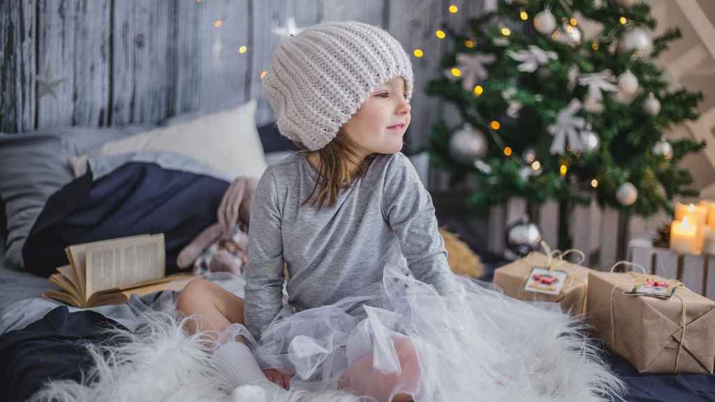 Niña con regalos junto a un árbol navideño / PIXABAY