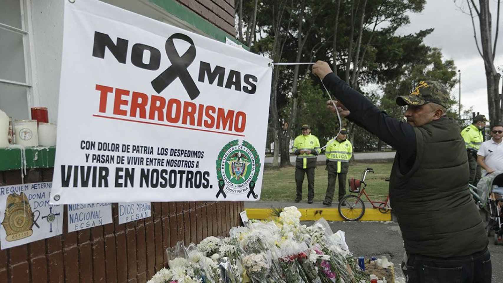 Un hombre extiende una pancarta durante un homenaje a los cadetes muertos por la explosión del coche bomba contra la Escuela de Cadetes de la Policía General Santander en Colombia / EFE