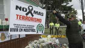 Un hombre extiende una pancarta durante un homenaje a los cadetes muertos por la explosión del coche bomba contra la Escuela de Cadetes de la Policía General Santander en Colombia / EFE