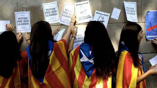 Menores con banderas independentistas pegan carteles animando a votar en el referéndum del 1-O durante el 'procés' / EFE