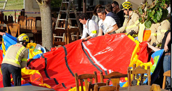 Varios operarios y bomberos retiran el castillo hinchable del restaurante Mas Oller, de Caldes de Malavella / EFE