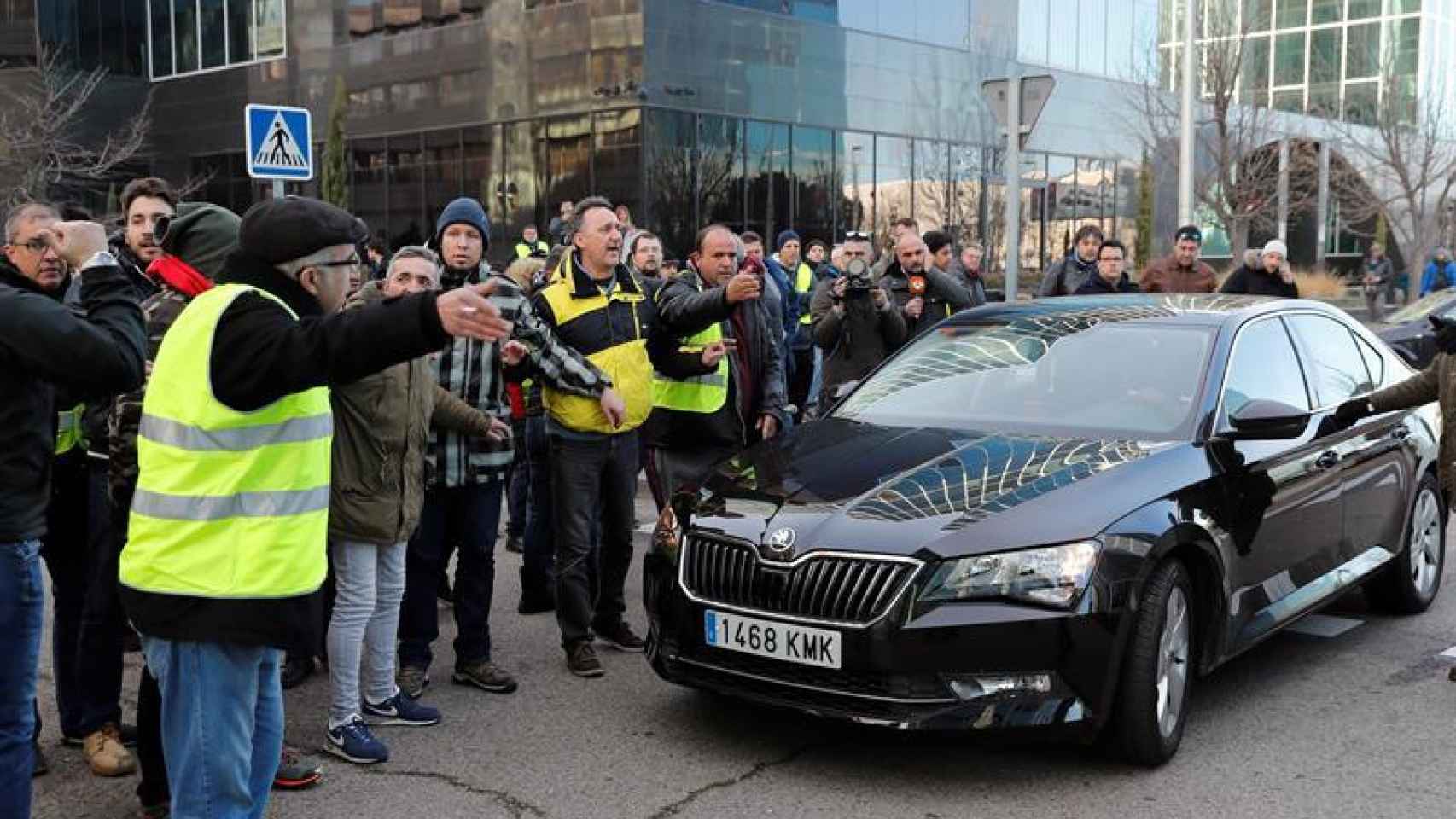 Un grupo de taxistas increpa al conductor de un vehículo VTC a las puertas de Ifema / EFE