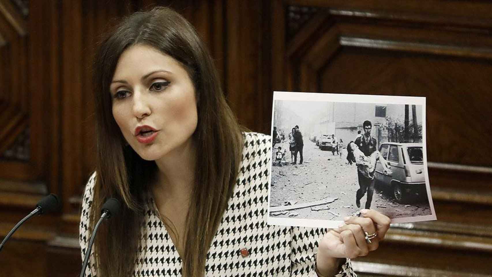 La presidenta del grupo parlamentario de Ciudadanos, Lorena Roldán, muestra una fotografía del atentado a la Casa Cuartel de la Guardia Civil de Vic en el debate de política general en el Parlament / EFE