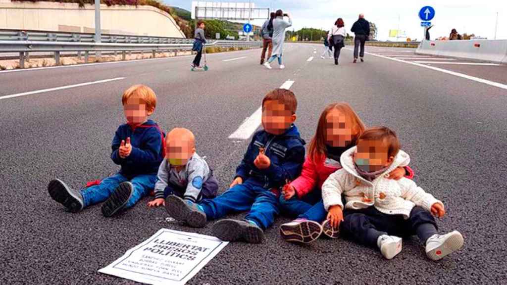 Bebés y niños sentados en la carretera con un cartel en el que se reclama la liberación de los presos políticos / CG