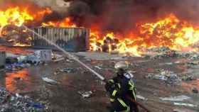 Un bombero tratando de apagar el incendio producido el exterior de una planta de reciclaje de papel en Arganda del Rey / TWITTER